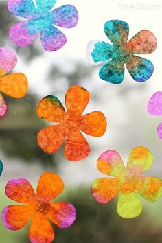 colorful paper flowers hanging from a window with watercolor paint on them and the words fun at days written below