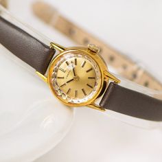 Description - Petite And Feminine Women’s Wristwatch. - Swiss Company Certina, Made In The 1960s In Switzerland. True “Mad Men” Style! - Face Face Is Gold With Silver Underside. Wristband Latch Is Silver. - Watch Is In Great Working Order And Has Been Serviced By A Professional. - Mechanical Movement Cal. 13-20 And Manual Winding. - New Black Leather Wristband (Size Small). Could Easily Be Replaced By A Jeweler For Another Color/Size Band. - Easily Transitions From Day To Night! Size Wristband I Vintage Everyday Watches, Everyday Vintage Watch, Brown Retro Formal Watch, Casio Vintage Watch, Gold And Silver Watch, Purple Watch, Vintage Swatch Watch, Acrylic Bracelet, Red Watch