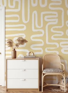 a white chair sitting next to a dresser in front of a wall painted with yellow and white paint