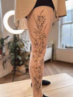 a woman's legs with flowers and leaves tattooed on the lower part of her leg