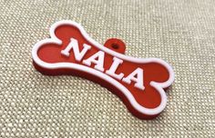 a red and white dog bone with the word'nala'written on it