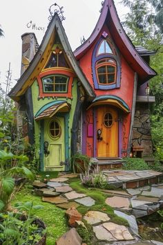 a colorful house with lots of windows and steps leading up to the front door is surrounded by greenery