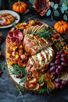 a platter filled with meat, fruit and crackers next to other food items