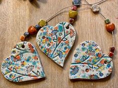 two ceramic heart shaped ornaments on a table with beaded necklaces and beads around them