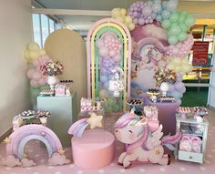 a table with balloons, unicorns and other items on it in a room filled with tables