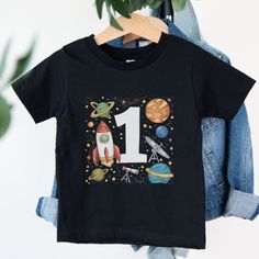 Welcome to Maddy & George Designs! We are excited to present our exclusive collection of baby t-shirts, each meticulously crafted to order. Unlike off-the-shelf products, every t-shirt is individually made with high-quality materials and careful printing techniques to ensure exceptional quality. Since each item is tailor-made for your little one, please allow 3-5 business days for us to prepare your order before shipping. The wait will be well worth it! **Product Information** Our baby t-shirts First Birthday Tops With Cartoon Print And Short Sleeves, Crew Neck Top With Cartoon Print For First Birthday, Cartoon Print Short Sleeve Tops For First Birthday, First Birthday Crew Neck Shirt With Graphic Print, First Birthday Graphic Print Crew Neck Shirt, Graphic Tee For First Birthday With Short Sleeves, Birthday Gift Number Print Short Sleeve Top, Birthday Black T-shirt With Cartoon Print, Cotton Number Print T-shirt For Birthday