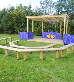 a wooden bench sitting on top of a lush green field next to a blue and yellow structure