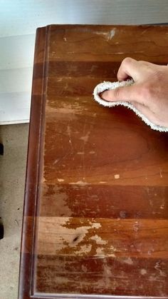 a person cleaning a wooden table with a rag