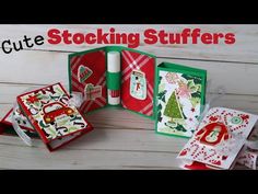 an open book with christmas cards inside on a wooden table next to some wrapping paper