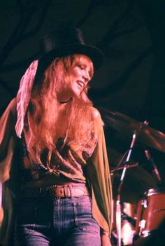 a woman with long blonde hair wearing a top hat and holding a microphone in her hand