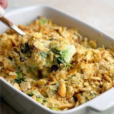 a casserole dish with broccoli and cheese being spooned into it