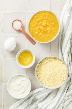 three bowls with different types of food in them on a white tile floor next to an egg and spoon