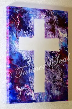 a white cross painted on top of a purple and blue wall