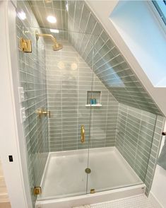 a bathroom with a walk in shower next to a toilet and sink under a slanted ceiling