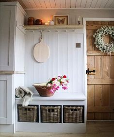 a white bench with baskets and flowers on it in front of a wooden paneled wall