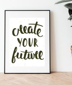 a black and white poster with the words create your future on it next to a potted plant