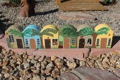 a group of small houses sitting on top of a rock covered ground next to a tree