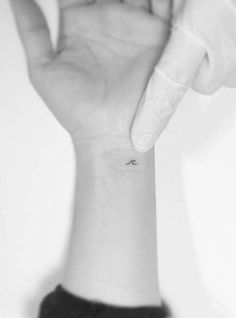 a person holding their hand up with a small tattoo on it's left wrist