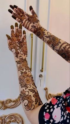 a woman with henna on her hands and arm is holding something in the air