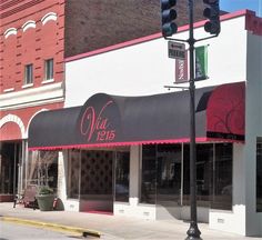 an empty street corner in front of a store with red and white awnings