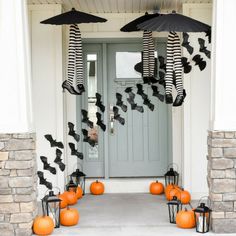 a front porch decorated for halloween with pumpkins and black bats hanging from the ceiling