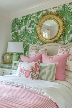 a bed with pink and green pillows in front of a mirror