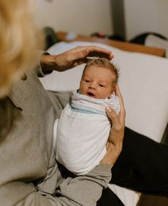 a woman holding a baby wrapped in a blanket