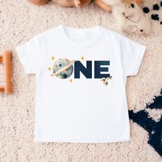 a white t - shirt with the word one printed on it next to stuffed animals