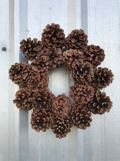 a wreath made out of pine cones hanging on the side of a white door,