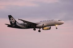 an air new zealand plane flying in the sky at dusk with its landing gear down