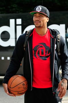 a man holding a basketball standing in front of a sign with the word d on it