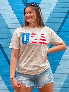 a woman standing in front of a blue brick wall with the word usa on it