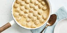 a white bowl filled with meatballs next to a plate and spoon on top of a table