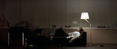 a man laying on a couch under a lamp in a living room with dark lighting