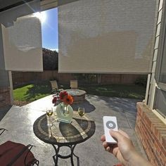 a person holding a remote control in front of a table with flowers and wine glasses on it