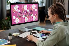 a woman sitting at a desk in front of a computer with pink flowers on it