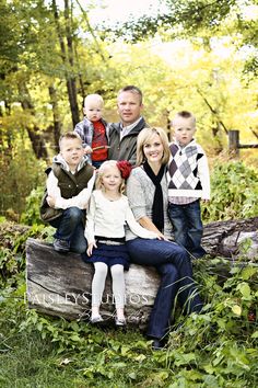 a family sitting on a log in the woods