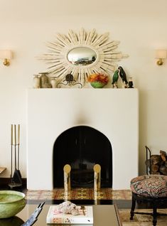 a living room filled with furniture and a fire place under a sunburst mirror