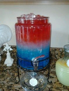 a red, white and blue candle sitting on top of a counter next to a vase