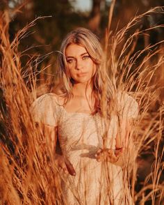 a woman standing in tall grass looking at the camera