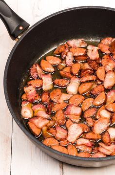 the food is being cooked in the skillet on the wooden table next to the utensils