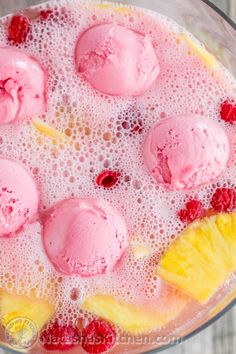 an ice cream dessert with raspberries and pineapples in a glass bowl