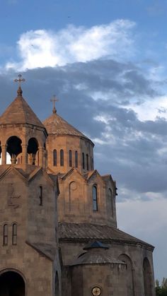 an old church with steeple and bell towers under a cloudy blue cloud filled sky