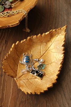 a leaf shaped bowl with two charms sitting on top of it next to other items