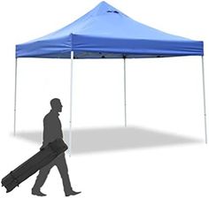 a man walking past a blue tent with a rolling bag on it's side