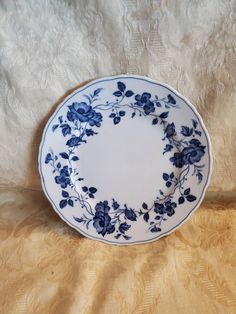 a blue and white plate sitting on top of a cloth covered tablecloth with flowers