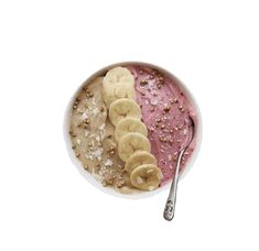 a bowl filled with bananas and granola on top of a white table next to a spoon