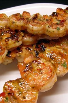 shrimp skewers on a white plate covered in sauce