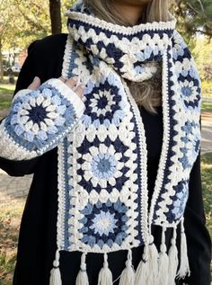 a woman wearing a blue and white crocheted scarf with tassels on it