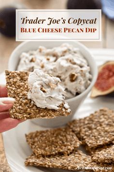 a person is holding up a cracker to show off their cheese pecan dip